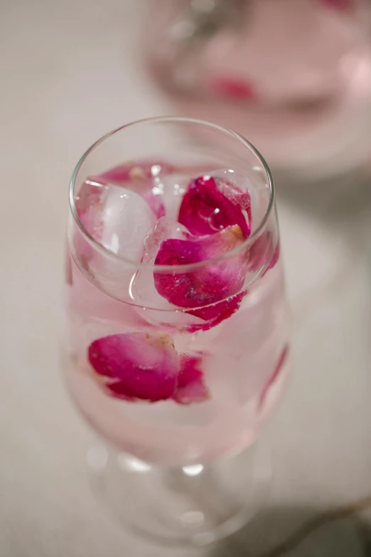 a close up of a glass of water with flowers in it, large individual rose petals, infused, polished, ice
