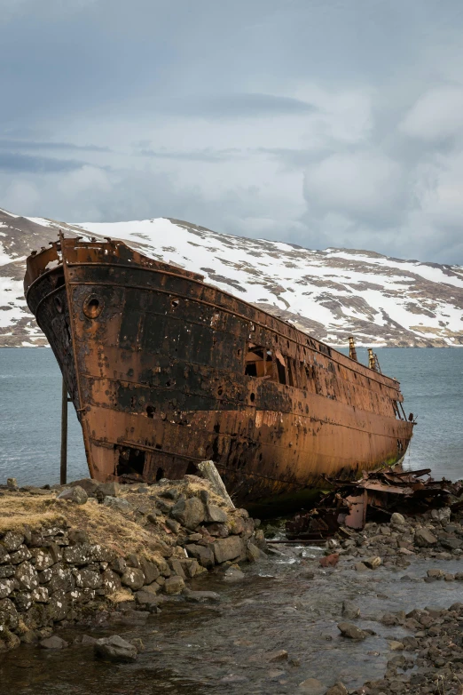 a rusted ship sitting on top of a rocky shore, snowy fjord, today's featured photograph, multiple stories, ((rust))