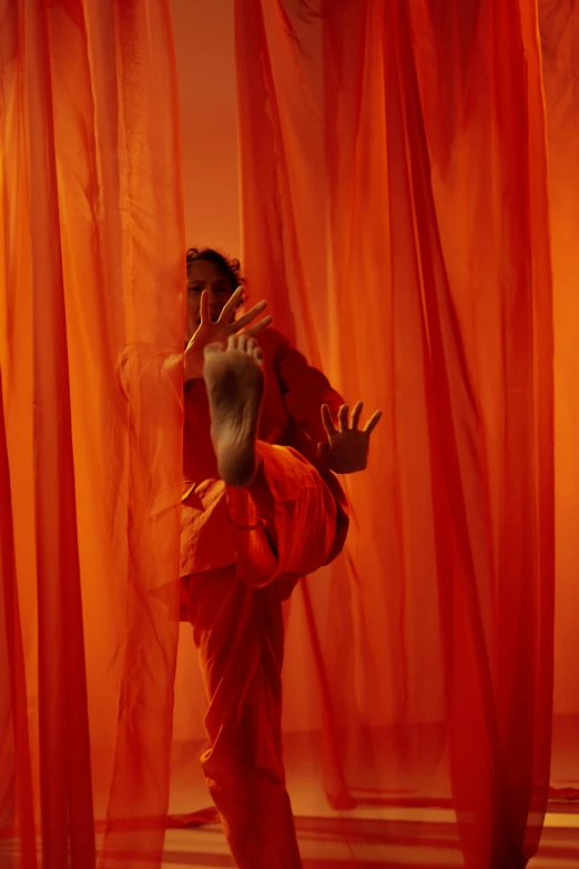 a woman standing in front of a red curtain, by Nathalie Rattner, pexels contest winner, conceptual art, in orange clothes) fight, contemporary dance, hindu aesthetic, showstudio