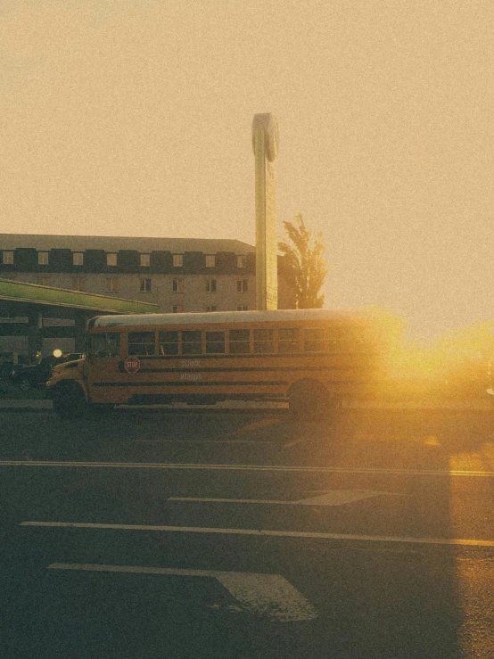 a school bus driving down a street next to a tall building, an album cover, inspired by Elsa Bleda, pexels contest winner, sunfaded, bus station exploded, summer morning light, grainy movie still