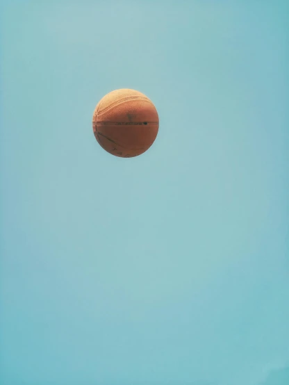 a basketball flying through the air with a blue sky in the background, by Quint Buchholz, postminimalism, joel meyerowitz, orange: 0.5, color photograph, light tan