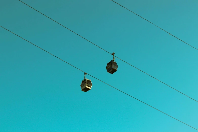 a couple of boxes sitting on top of a power line, inspired by Rene Magritte, unsplash, postminimalism, gondolas, light blue clear sky, tram, instagram post