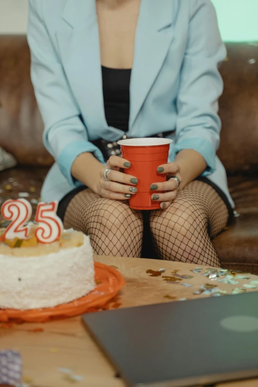 a woman sitting on top of a couch next to a cake, inspired by Elsa Bleda, trending on unsplash, awkwardly holding red solo cup, he is about 2 5 years old, fishnet tights, at a birthday party