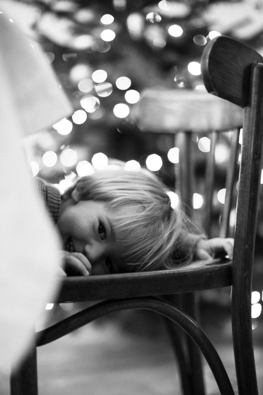 a little girl laying on a chair in front of a christmas tree, a black and white photo, by Albert Welti, tumblr, realism, bokeh. i, sitting alone in a cafe, boy, a blond
