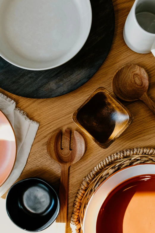 a wooden table topped with plates and utensils, inspired by Peter de Sève, trending on unsplash, black and orange colour palette, close-up product photo, bay area, inspect in inventory image