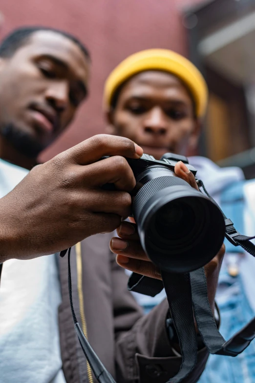 two men standing next to each other holding a camera, a picture, pexels contest winner, african cyberpunk wizards, zoomed in, looking down on the camera, professional photo-n 3