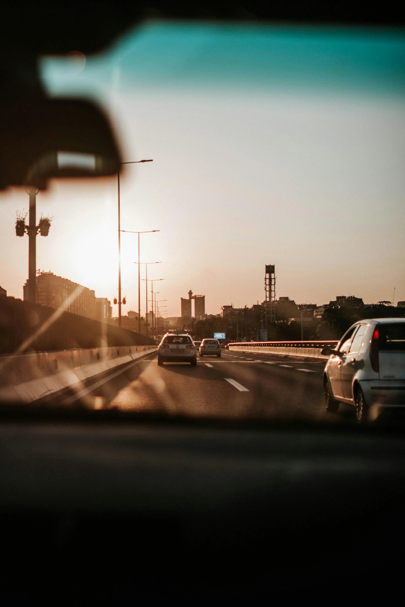 a view of the sun through the windshield of a car, pexels contest winner, happening, urban view in the distance, highways, cars and people, side light