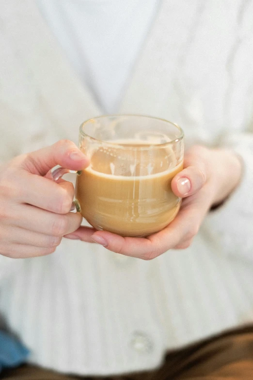 a close up of a person holding a cup of coffee, beige mist, with clear glass, product shot, beige