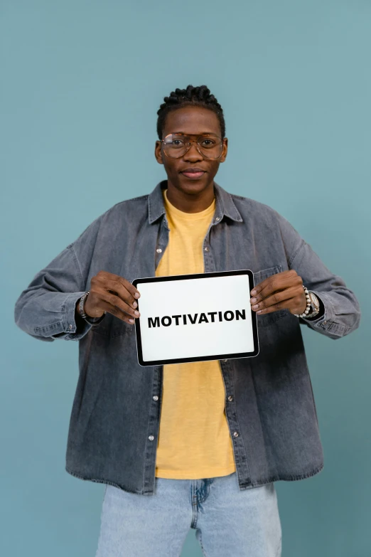 a man holding a sign that says motivation, an album cover, by Matthias Stom, trending on unsplash, black teenage boy, non-binary, malaysian, adut akech