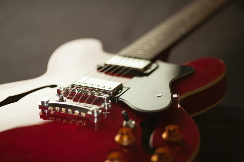 a red electric guitar sitting on top of a table, by Tom Bonson, pexels contest winner, close - up on detailed, extremely polished, lachlan bailey, high resolution