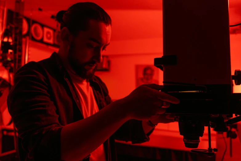 a man that is standing in front of a camera, by Alejandro Obregón, pexels contest winner, holography, red light, microscope, cinematic counter light, photolithography