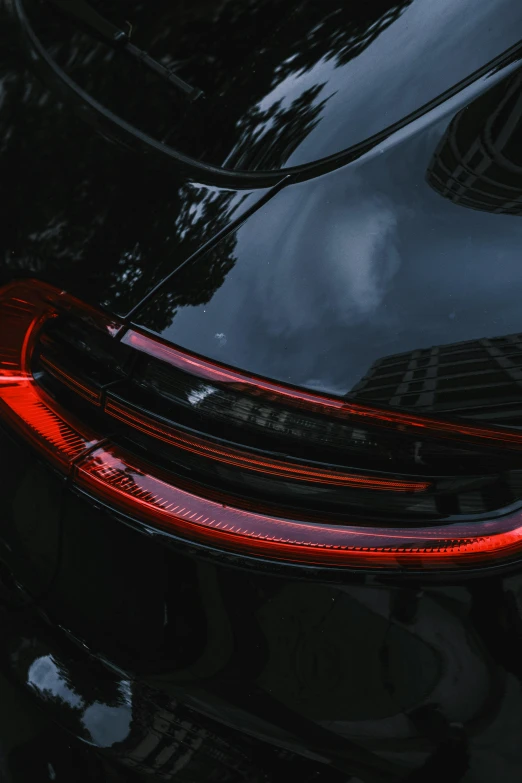 a close up of the tail lights of a black car, pexels contest winner, glossy surface, avatar image, 2 0 % pearlescent detailing, porsche