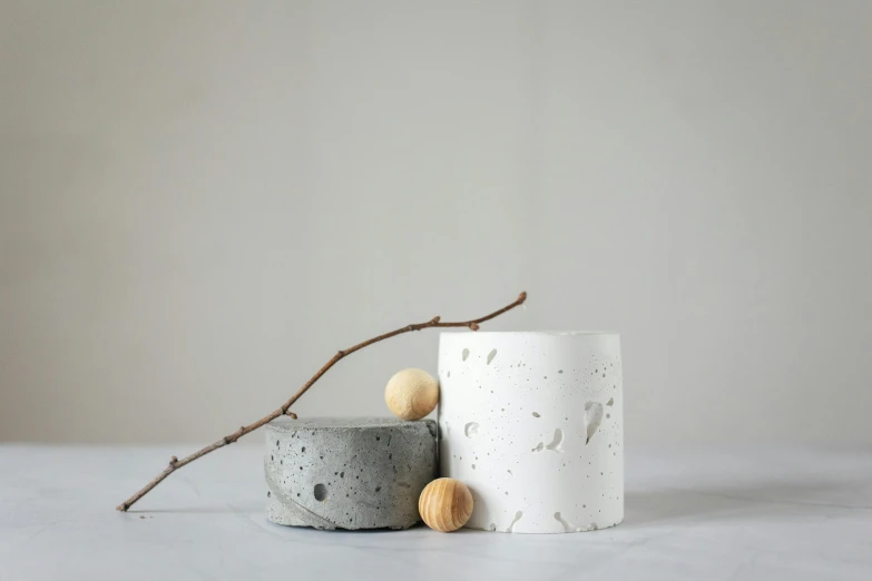 a couple of cups sitting on top of a table, an abstract sculpture, inspired by Hendrik Gerritsz Pot, unsplash, concrete art, white with black spots, seeds, product display photograph, birch