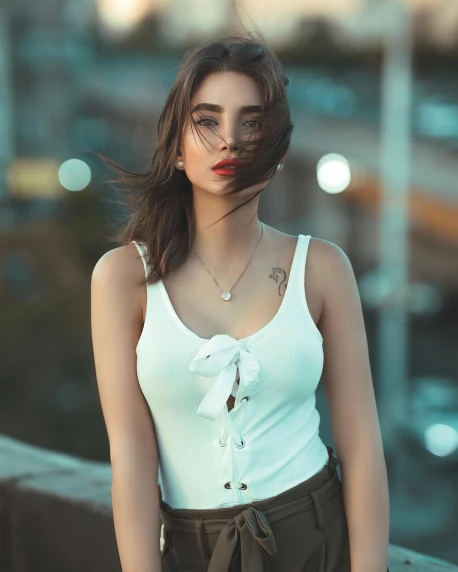 a beautiful young woman standing next to a body of water, a colorized photo, inspired by Elsa Bleda, trending on pexels, renaissance, wearing white camisole, posing in an urban street, portrait of sherlyn chopra, gif