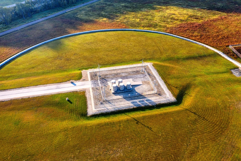 a large building sitting on top of a lush green field, land art, gigantic landing pad, in louisiana, looking down on the view, monument