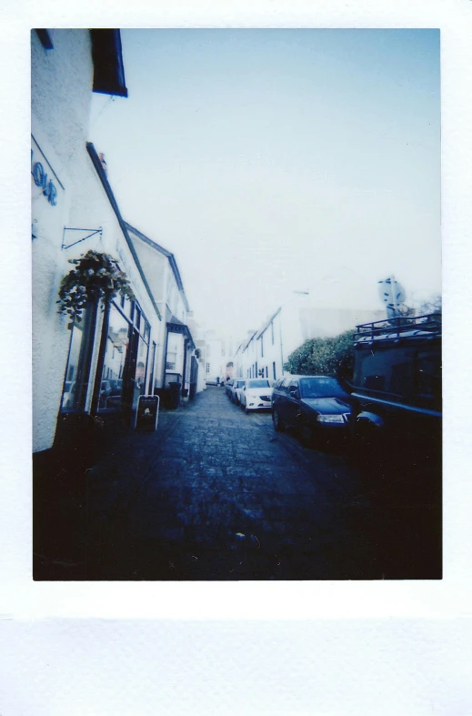 a street with cars parked on the side of it, a polaroid photo, straight camera view, dreamy hazy, alleys, holywood scene