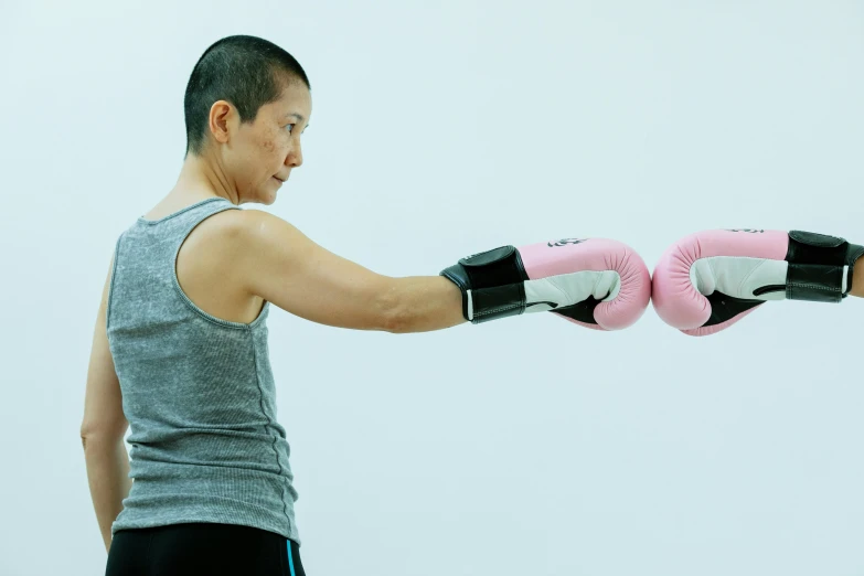 a woman in a gray tank top and pink boxing gloves, inspired by Guo Chun, shin hanga, reaching out to each other, profile image, aged 4 0, upper body image