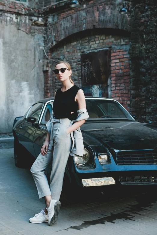 a woman standing next to a parked car, by Zofia Stryjenska, pexels contest winner, baggy pants, elegant fashion model, with sunglasses, post grunge