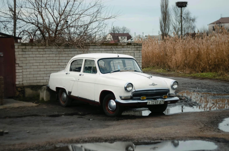 a white car parked in front of a brick wall, pexels contest winner, photorealism, 1962 soviet, square, preserved historical, high quality image