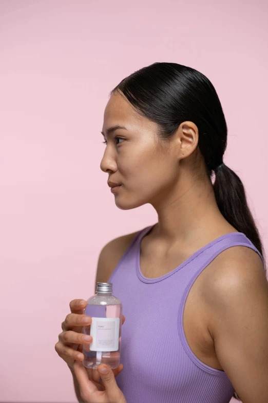 a woman in a purple tank top holding a bottle of water, inspired by Kanō Tan'yū, trending on pexels, side of head, silicone skin, detailed product image, asian face