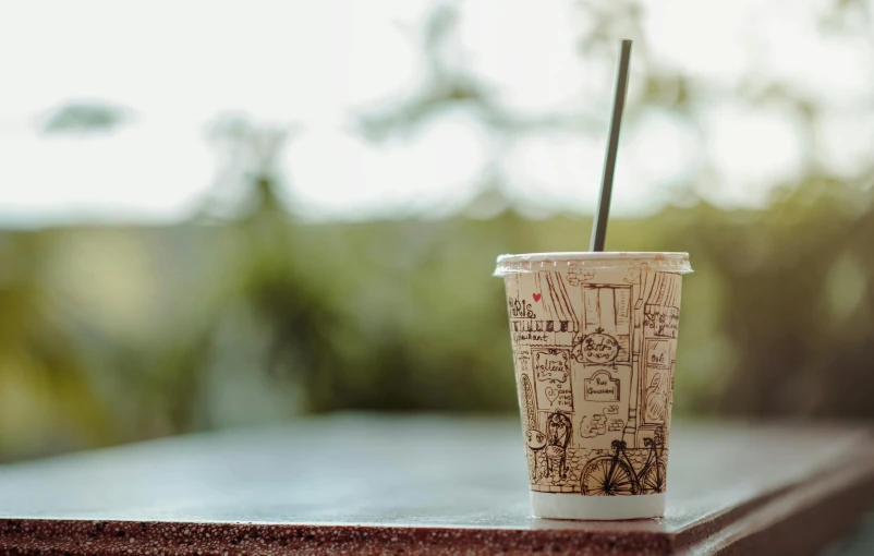 a paper cup with a straw sitting on a table, unsplash, photorealism, background image, al fresco, multiple stories