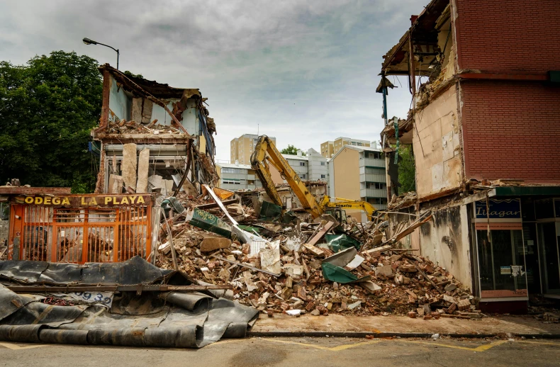 a pile of rubble sitting on the side of a road, a photo, inspired by Thomas Struth, unsplash, in a tropical and dystopic city, buildings collapsed, te pae, sunken square