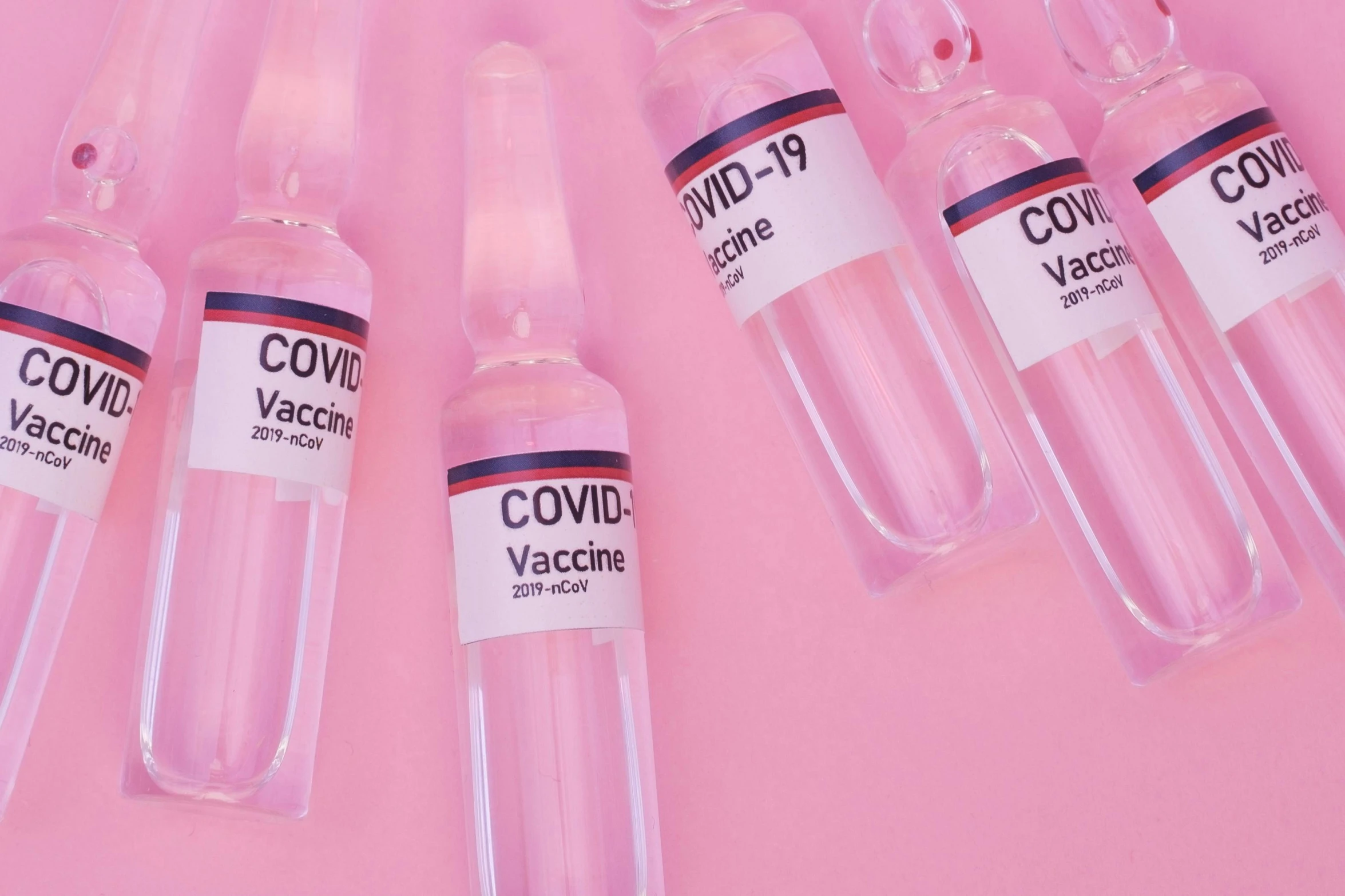 a group of vials sitting on top of a pink surface, trending on pexels, syringe, label, covid, conor walton