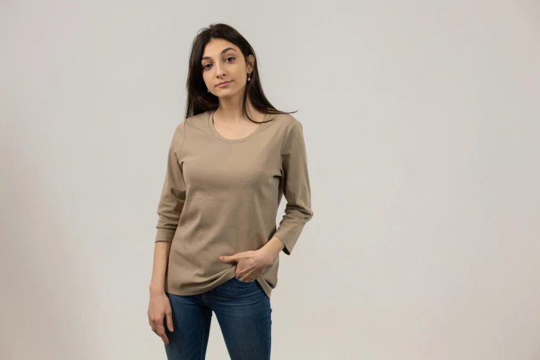 a woman standing with her hands in her pockets, a portrait, pexels contest winner, brown shirt, confident relaxed pose, product shot, rounded beak