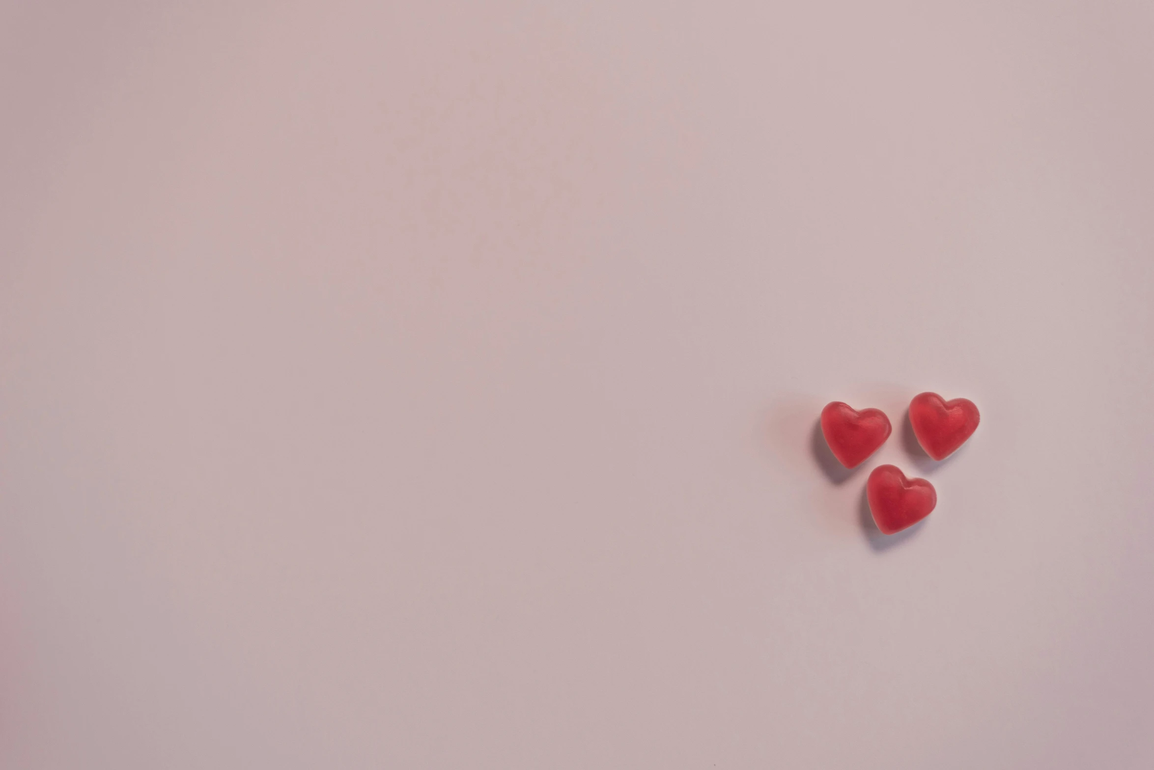 a couple of red hearts sitting on top of a white surface, a picture, by Emma Andijewska, pink background, gif, threes, pills