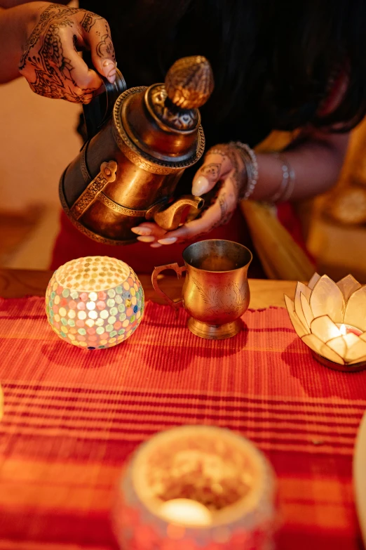 a woman pouring tea into a cup on a table, hindu aesthetic, illuminated features, cups and balls, lit up