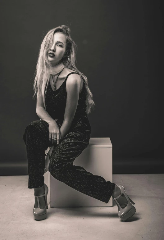 a woman sitting on top of a white box, an album cover, unsplash, realism, with long blond hair, dark. studio lighting, doing a sassy pose, cl