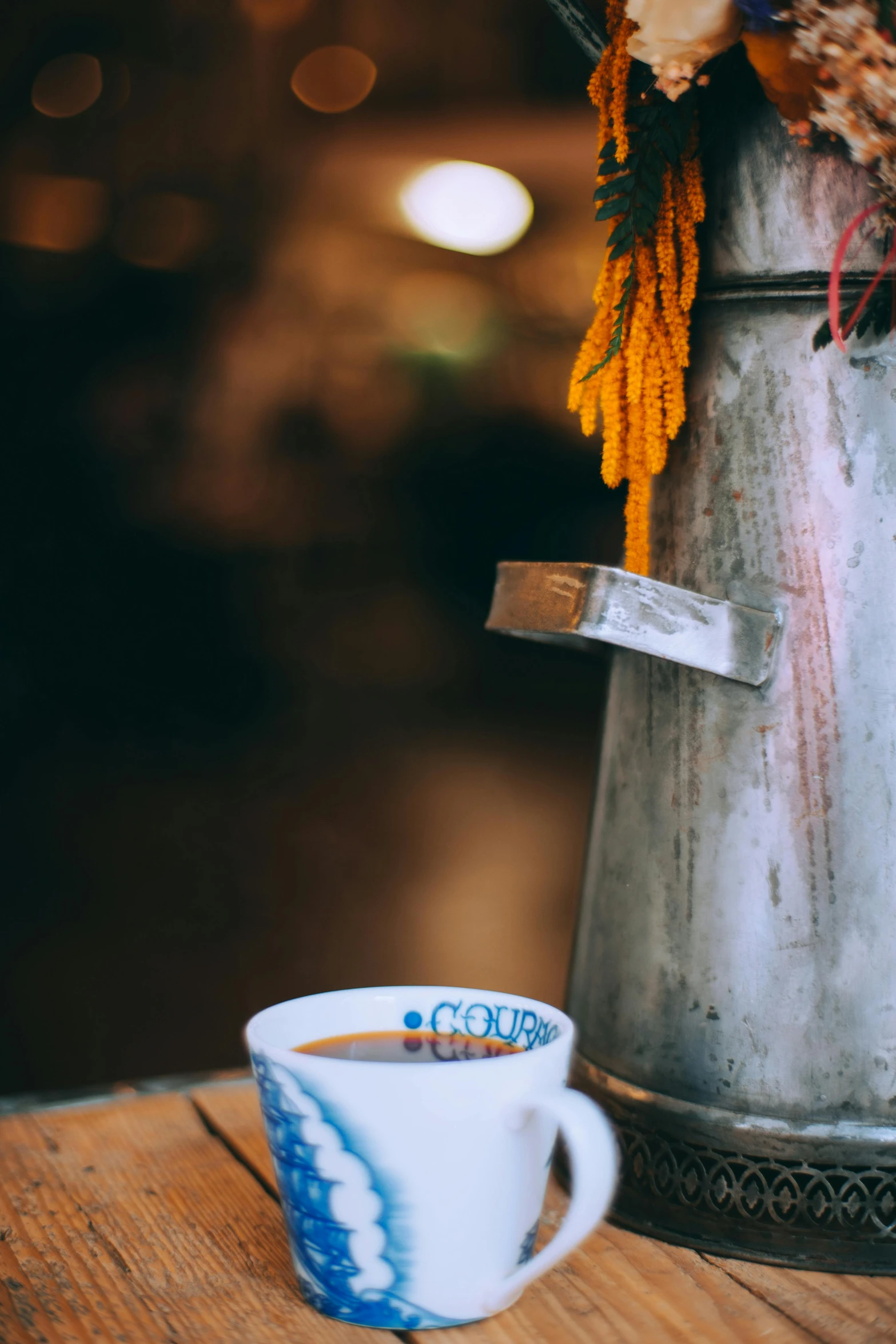 a cup of coffee sitting on top of a wooden table, a still life, by Elsa Bleda, trending on unsplash, watering can, from egypt, local close up, vibrant scene