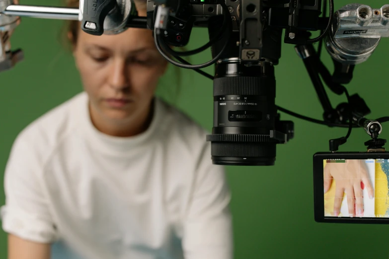 a close up of a person holding a camera, looking towards the camera, close up to the screen, production quality cinema model, she is facing the camera