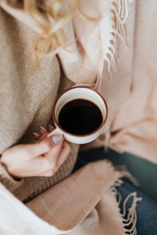 a close up of a person holding a cup of coffee, muted browns, curated collections, woman, cuddly