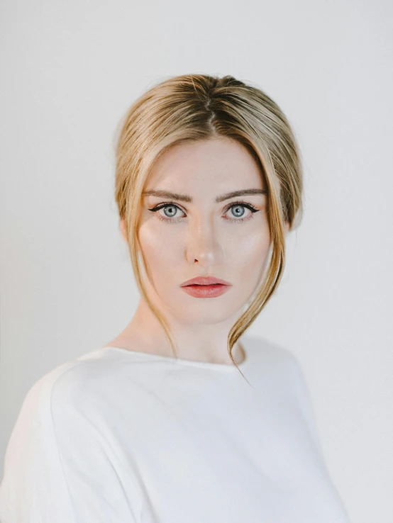 a woman in a white shirt posing for a picture, a character portrait, inspired by Louisa Matthíasdóttir, trending on unsplash, hyperrealism, imogen poots paladin, better known as amouranth, white backdrop, white prosthetic eyes