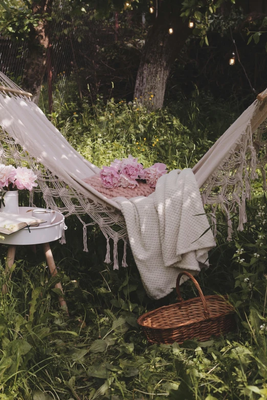 a hammock sitting on top of a lush green field, peonies, white tablecloth, exterior shot, daytime