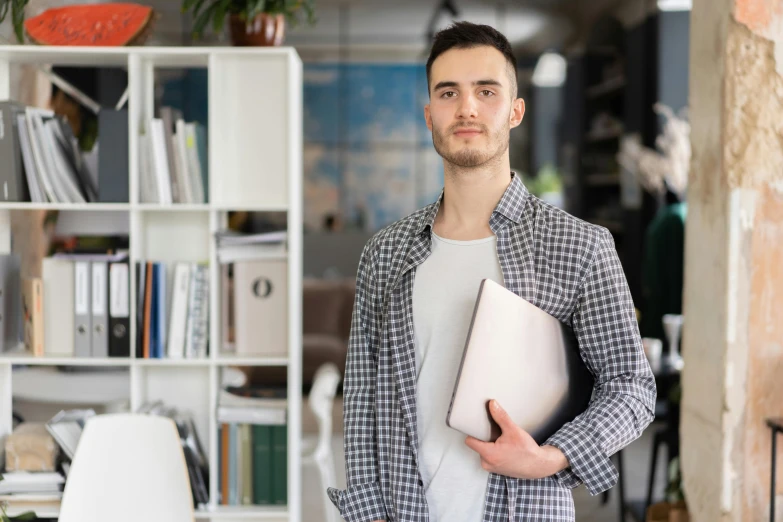 a man standing in a room holding a laptop, pexels contest winner, lean man with light tan skin, in the office, young man with short, lachlan bailey