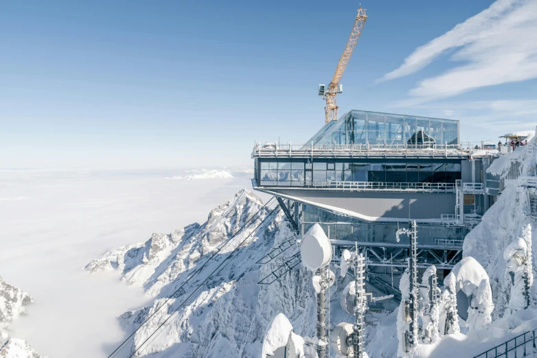 a group of people standing on top of a snow covered mountain, a detailed matte painting, by Matthias Weischer, pexels contest winner, bauhaus, sitting in a crane, huge glass structure, “ aerial view of a mountain, view from the side
