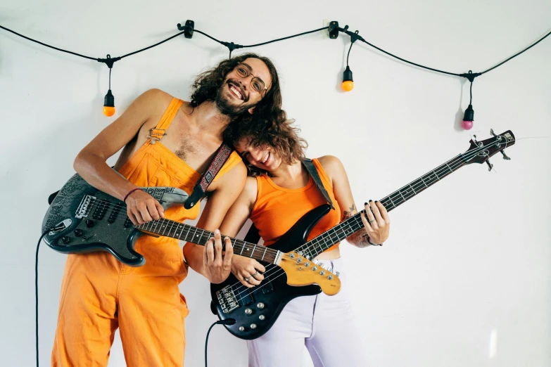 a man and a woman standing next to each other with guitars, pexels, antipodeans, wearing an orange jumpsuit, rocking out, bassist, wearing overalls