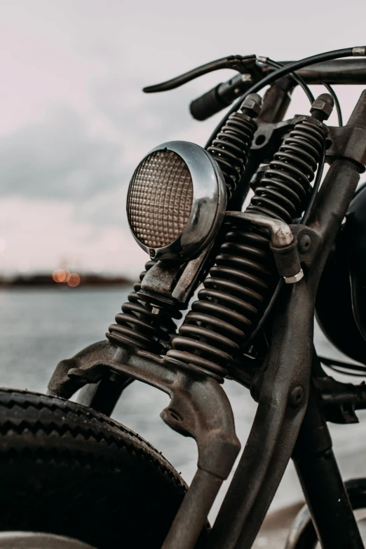 a motorcycle parked next to a body of water, pexels contest winner, extreme intricate metal details, a pair of ribbed, front profile shot, low quality photo