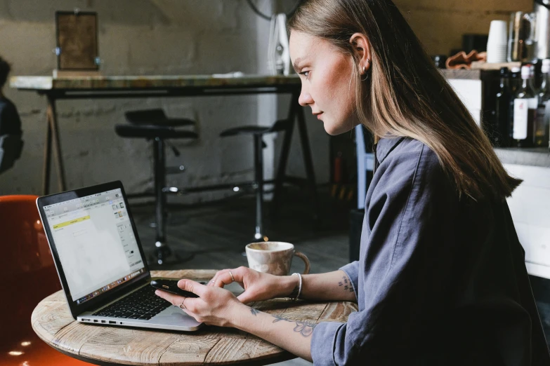 a woman sitting at a table using a laptop, a portrait, trending on pexels, realistic »