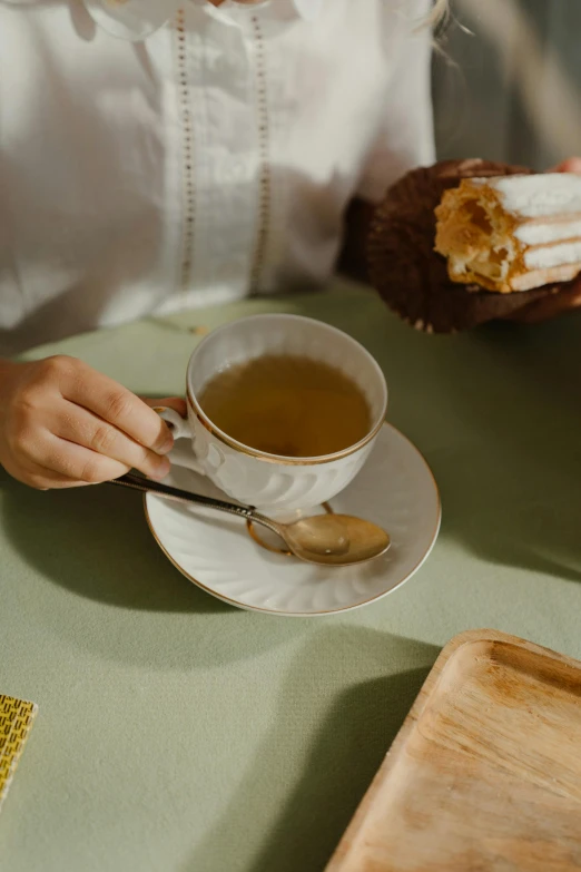 a woman sitting at a table with a cup of tea, a still life, trending on pexels, renaissance, pastry, green, thumbnail, square