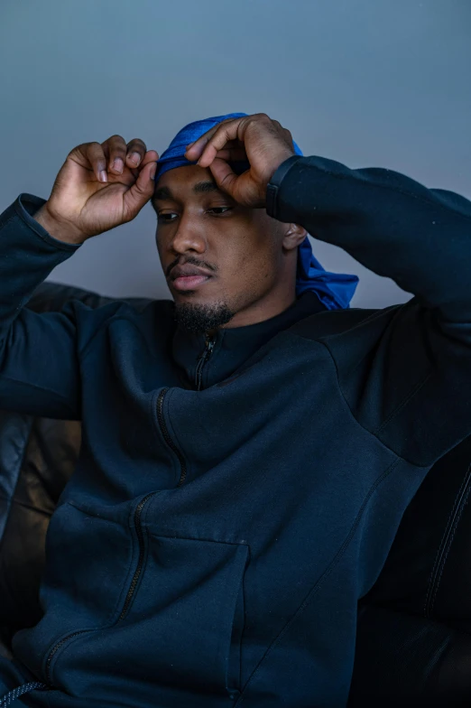 a man wearing a blue bandana sitting on a couch, inspired by Zhu Da, trending on pexels, visual art, 8k resolution. tupac, in a black hoodie, adam driver, mkbhd