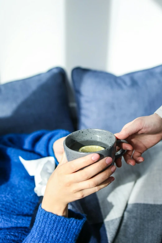 a woman sitting on a couch holding a cup, by Julia Pishtar, trending on unsplash, drinking cough syrup, square, green tea, close together