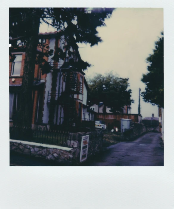 a street with cars parked on the side of it, a polaroid photo, unsplash, shin hanga, old house, \!cinestill 50d! film photo, residential area, hazy