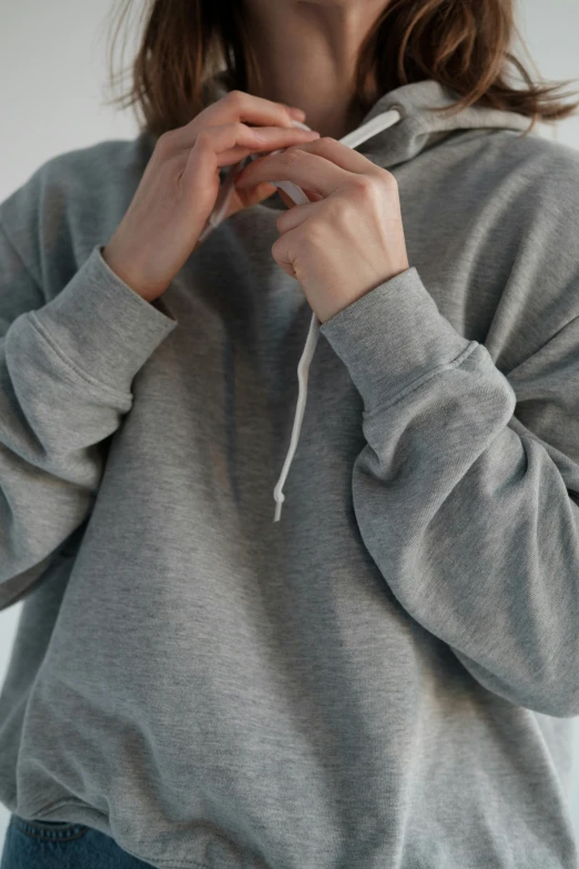 a woman in a grey hoodie poses for a picture, trending on pexels, low detail, detailed product image, zoomed in, product view