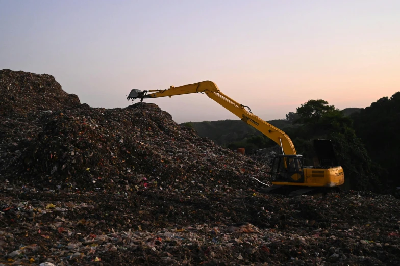 a bulldozer sitting on top of a pile of garbage, sun down, profile image