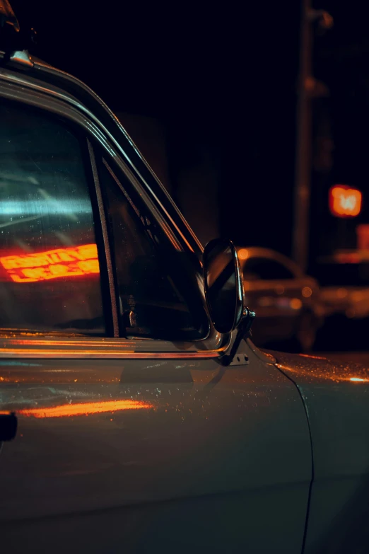 a car parked on the side of the road at night, an album cover, inspired by Elsa Bleda, unsplash, photorealism, 1 9 7 0 s car window closeup, orange lights, profile picture, nightlife