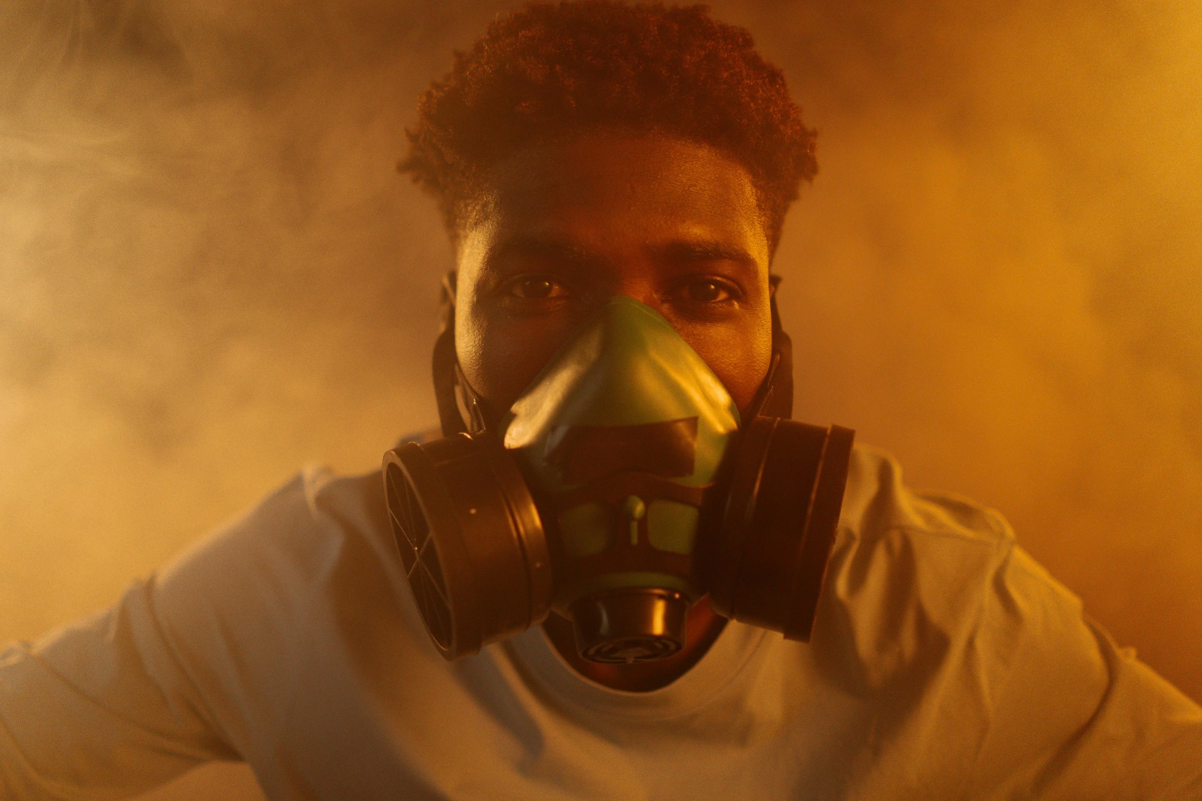 a man wearing a gas mask in a smoke filled room, afrofuturism, green facemask, awardwinning movie still, 2 1 savage, cleanest image