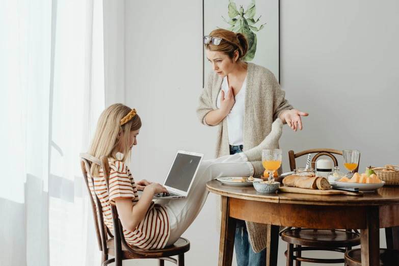 a woman and a little girl sitting at a table with a laptop, trending on pexels, figuration libre, casually dressed, sitting on chair, 1 5 0 4, ☕ on the table